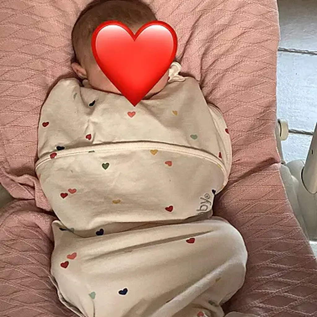Baby in Piep slaapzak met hartje emoticon over gezicht
