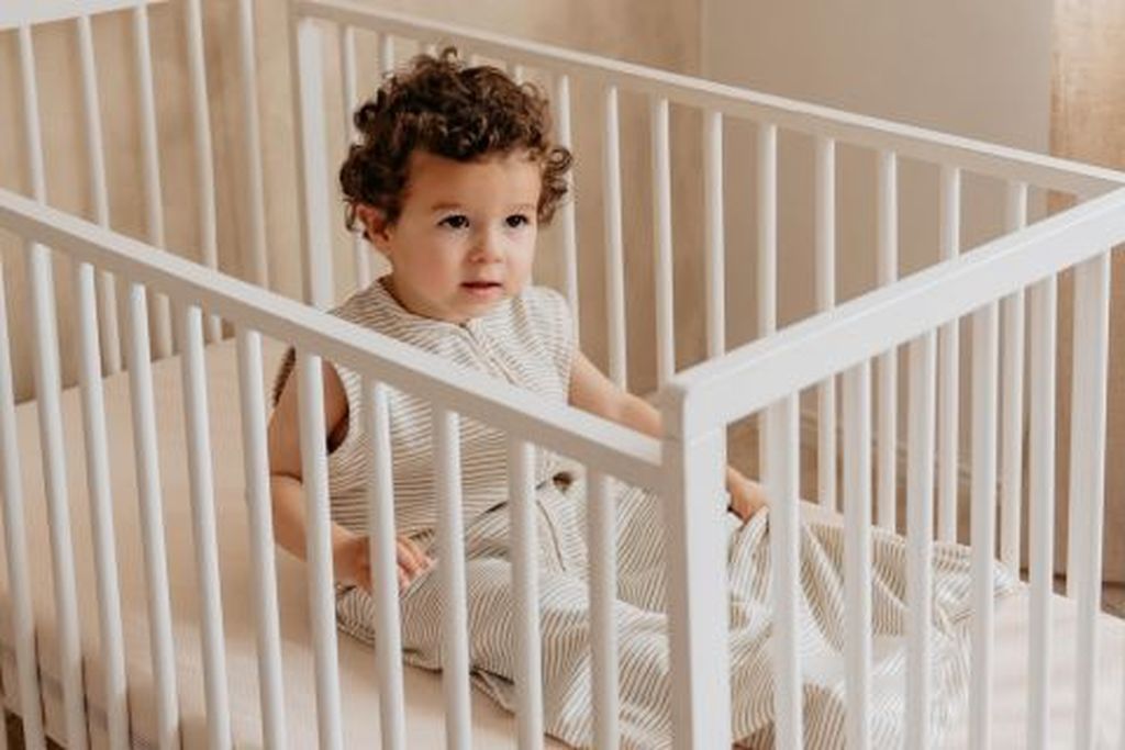 Toddler sitting in bed wearing a Bag 2 Seasons without sleeves
