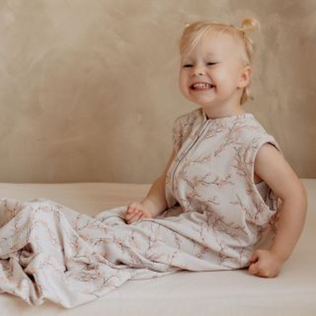 Toddler sitting on bed wearing Bag 2 Seasons sleepingbag without sleeves