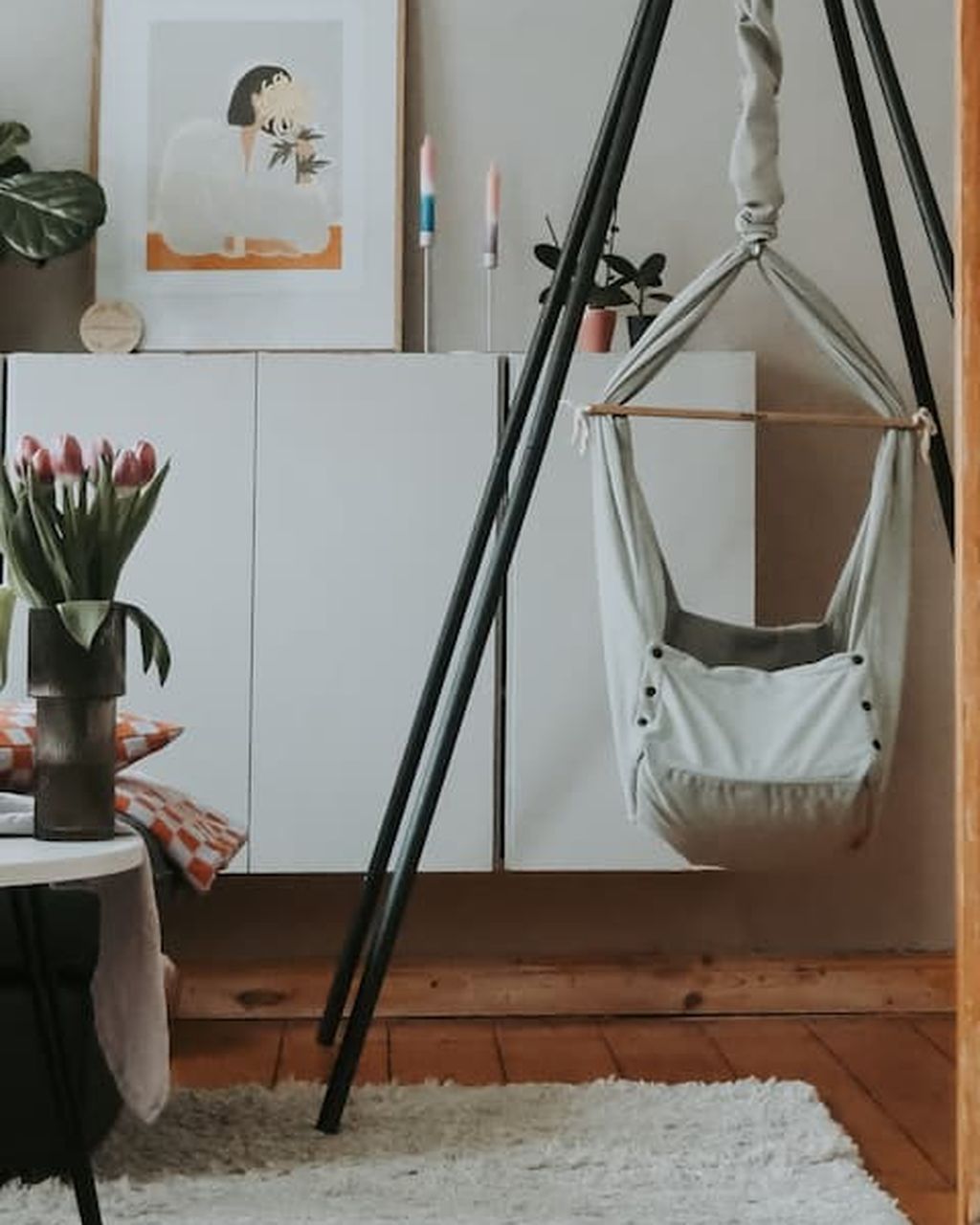 Graue Federwiege mit dunklem Motor und dunklem Tipi-Gestell im Wohnzimmer
