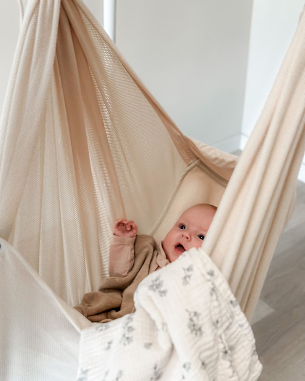 Ein Baby liegt glücklich in der NONOMO Federwiege