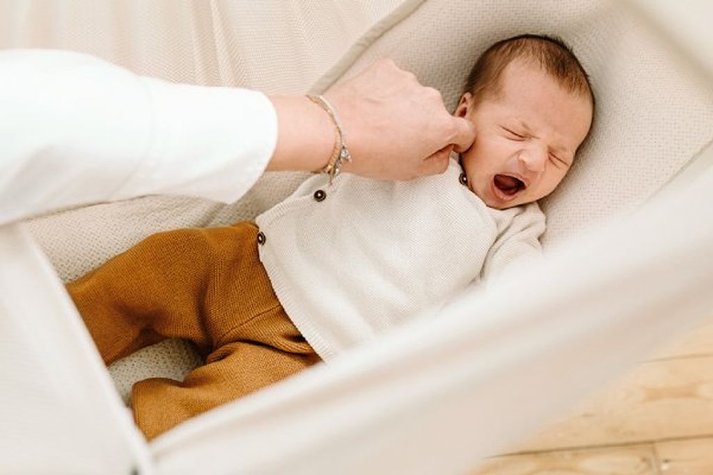 A baby yawns in a cozy hammock