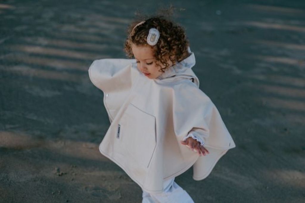 Vrolijk kindje in de regenponcho Chevron Cream