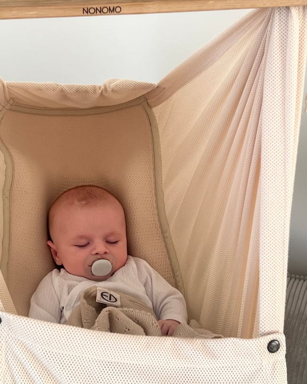 Baby mit Schnuller, das friedlich in einer beigen Babyhängematte schläft