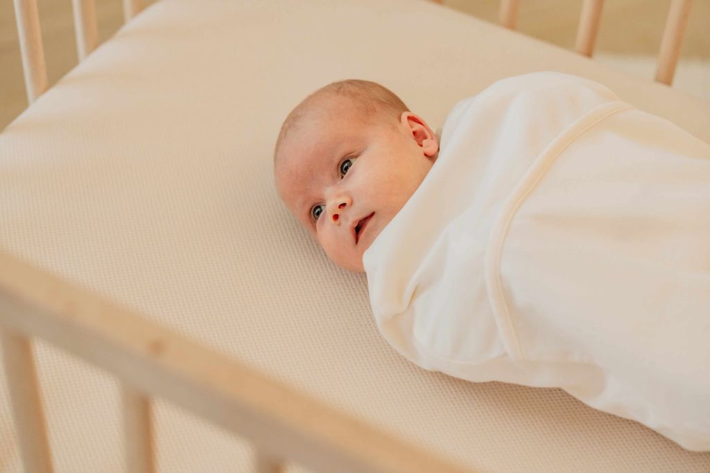 Een baby ligt op een AeroSleep Evolution matraspakket.
