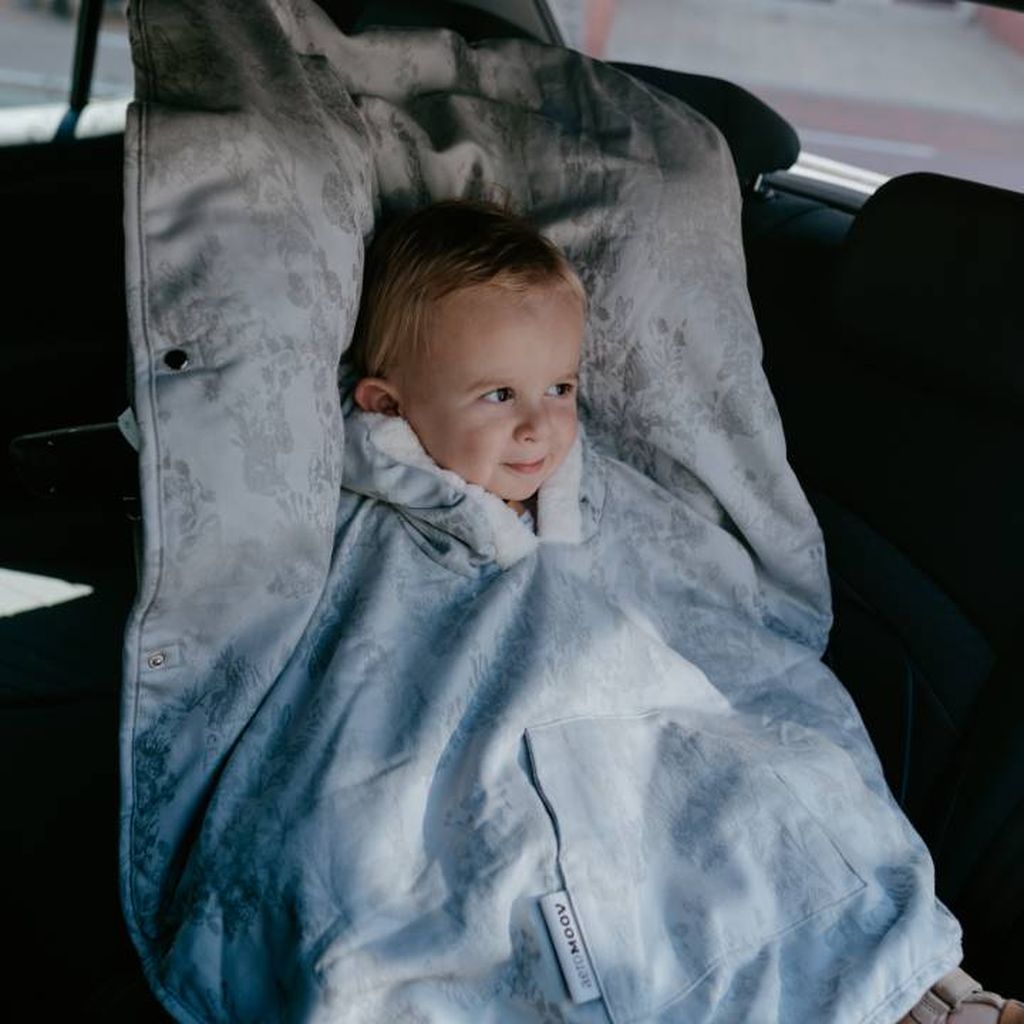 A toddler is sitting in a car seat and wearing a poncho