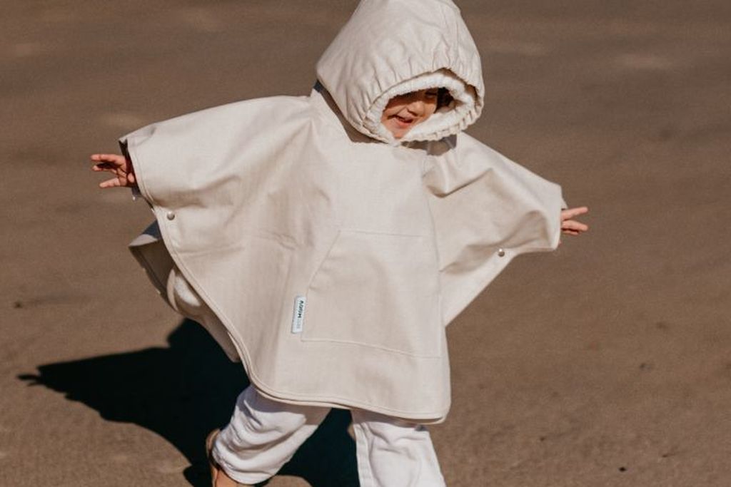 Toddler wearing a poncho while it is very windy