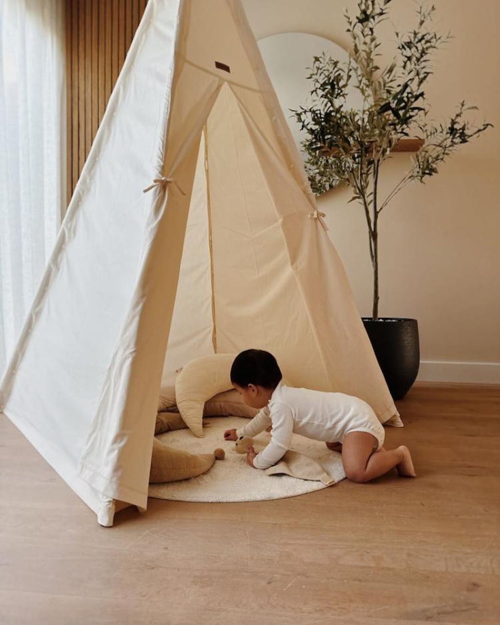 Kleinkind spielt in einem Tipi, das zu einem Zelt umgebaut wurde