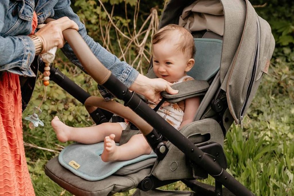 A smiling baby sits on an Air Layer in a stroller