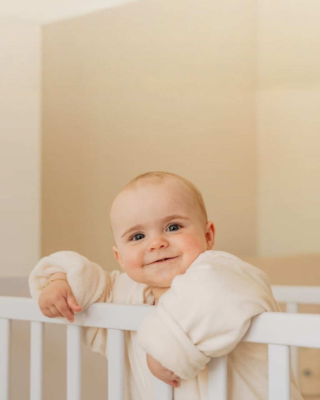 Baby standing in bed wearing sleeping bag