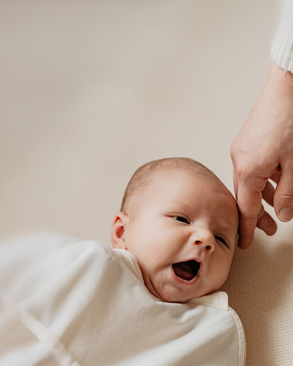 Yawning baby in bed with parents hand