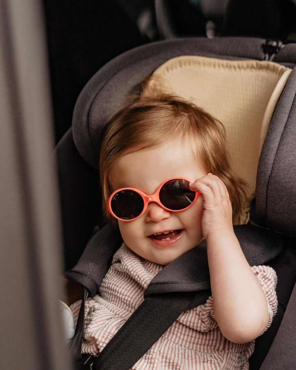 Happy toddler with sunglasses sitting in a car seat with an air layer