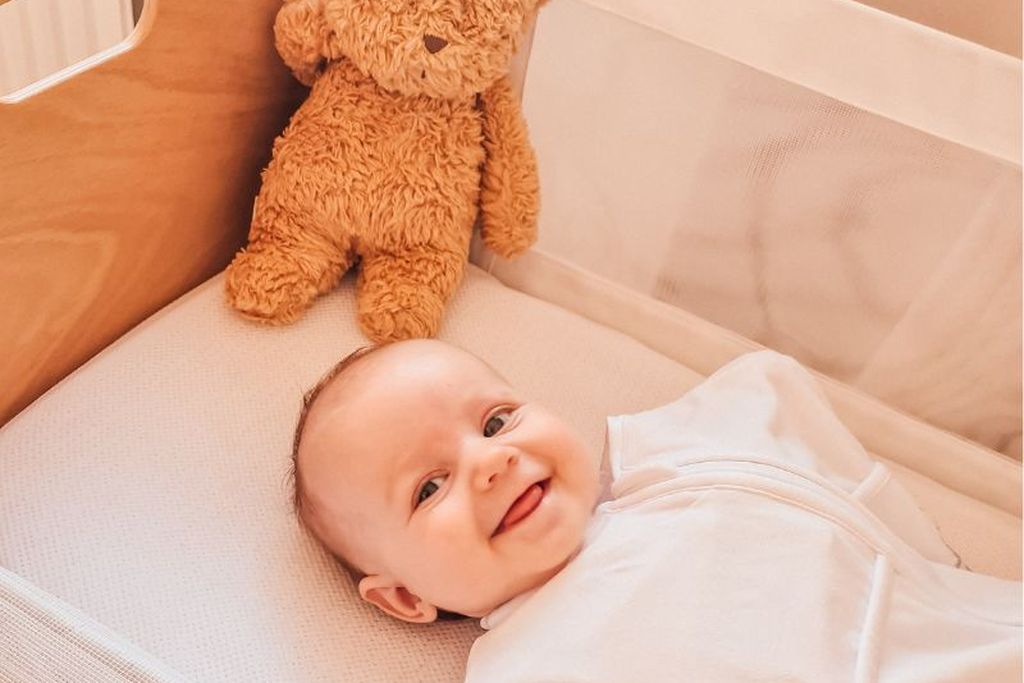Ein lächelndes Baby in einem Pucksack