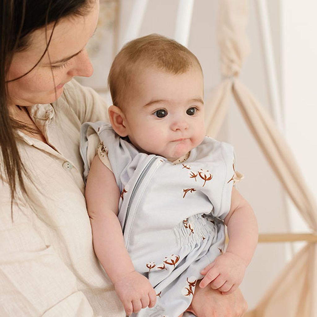 Ein müde aussehendes Baby wird in den Armen gehalten.