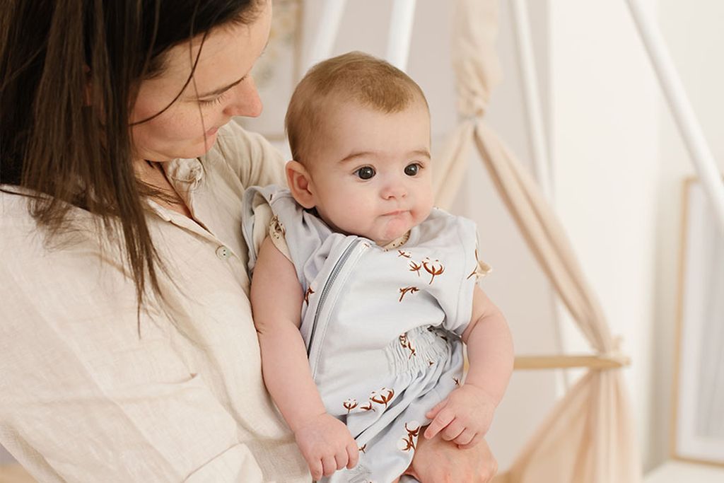 Ein müde aussehendes Baby wird in den Armen gehalten.