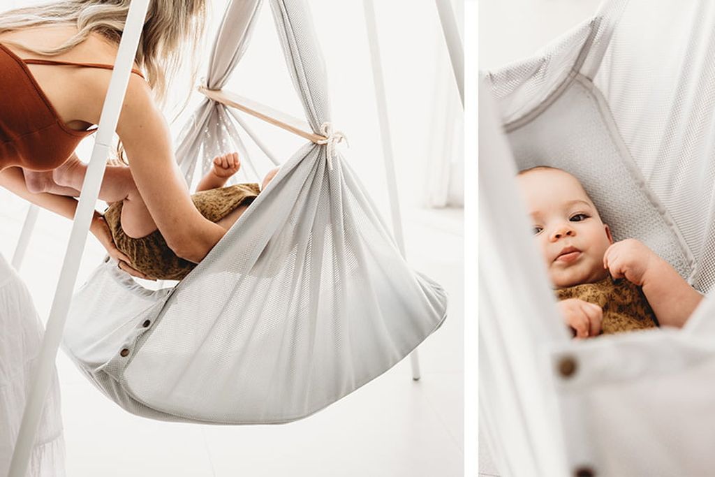 A woman gently places a baby in hammock