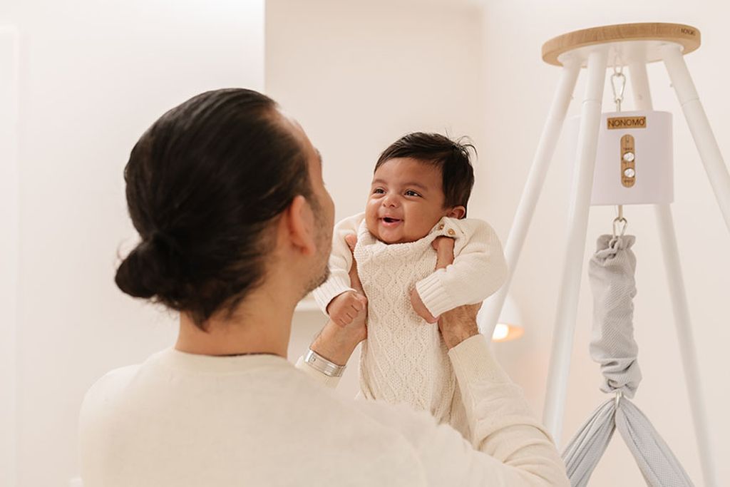 Das Baby wird im Arm gehalten. Im Hintergrund sieht man das NONOMO mit Tipi-Ständer und Move-Motor