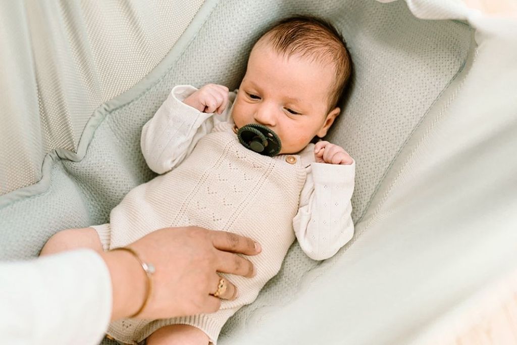Baby streckt sich in Federwiege
