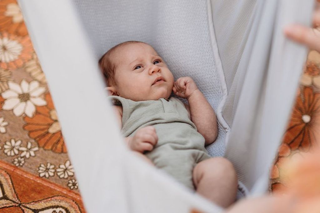 Ein Baby in einer grauen Federwiege
