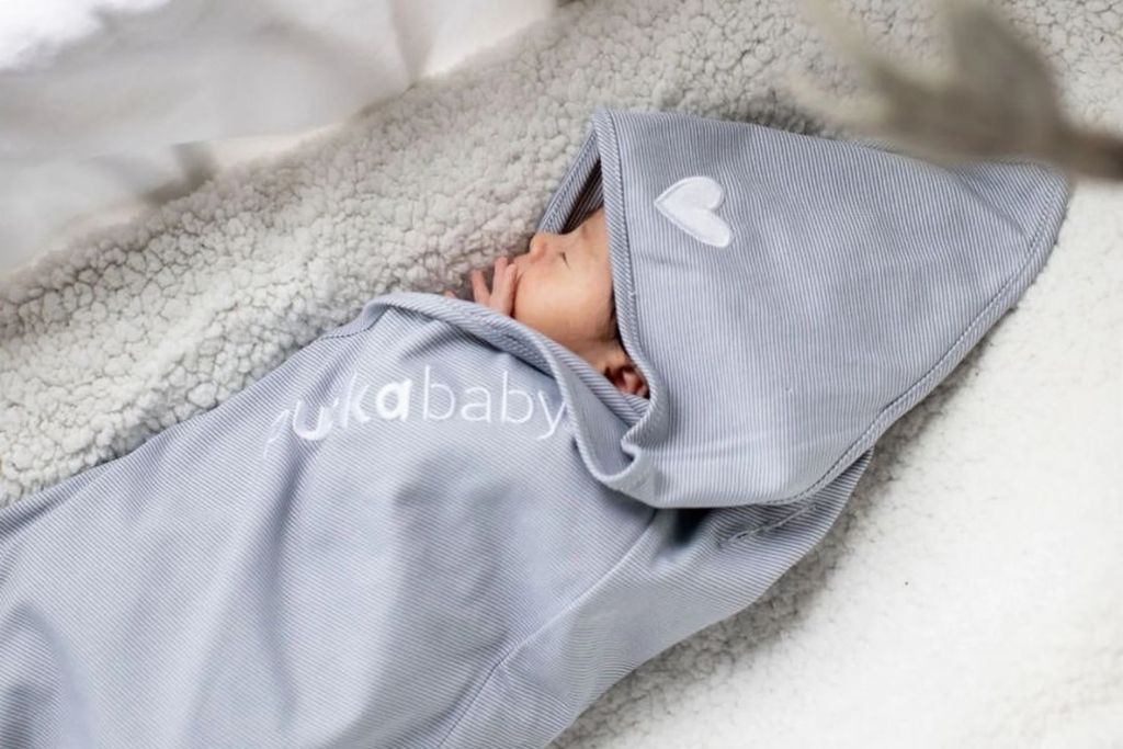 Baby in wrappingblanket, laying gin bed