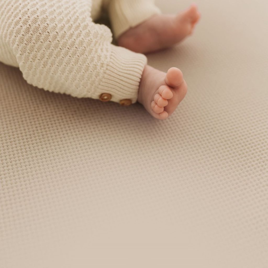 Close-up van de voeten van een baby op een geperforeerd hoeslaken