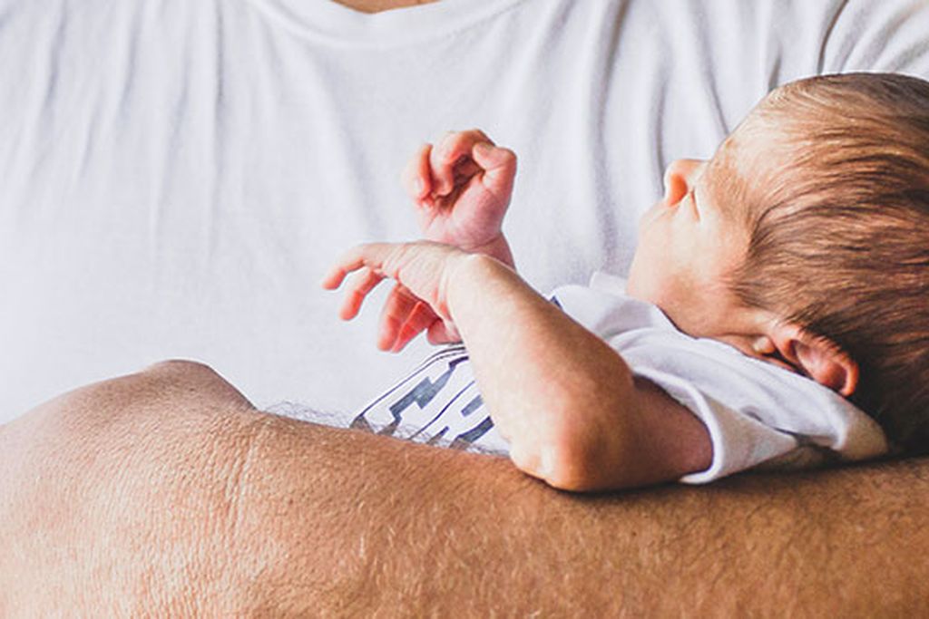 Das Baby wird liebevoll in den Armen eines Mannes getragen