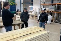 Mensen staan in een werkplaats met houten balken