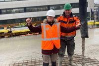 Twee bouwvakkers steken hun duim op tijdens het werk