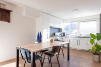 Ruime keuken met langwerpige eettafel met 4 stoelen in het midden en een grote groene plant in de hoek