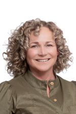 Lachende vrouw met blonde krullen en groene blouse.