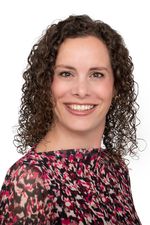 Portretfoto van een lachende vrouw met bruine krullen.