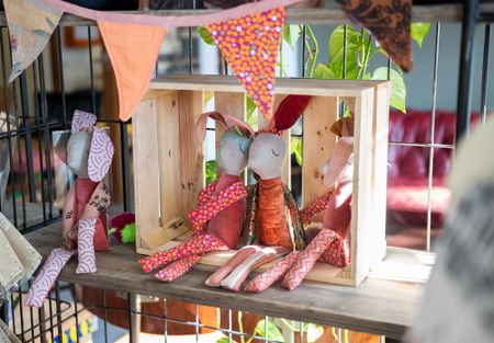 Een houten kast met in een houten kistje vier konijnknuffels gemaakt van stoffen met gekleurde prints.