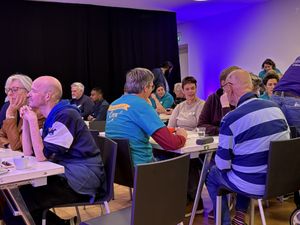 Een sfeervol verlichte ruimte met allemaal tafels met mensen eraan, die met elkaar in gesprek zijn.