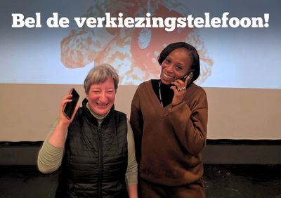 Twee vrouwen poseren met hun telefoon tegen hun hoor en lachen breed.