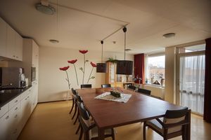 Keuken met grote mahoniehouten eettafel en 8 stoelen. Op de muur mooie grote klaprozen tot aan het plafond