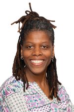 Lachende vrouw met dreadlocks en gekleurde blouse.