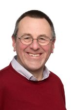 Lachende man met bril en rode trui.