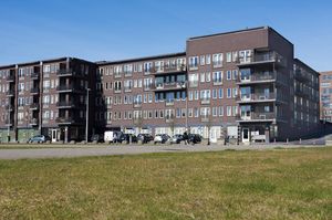 Gebouw van de locatie Anton de Kom. Vier verdiepingen en balkons. Invalidenparkeerplaatsen bij de ingang.
