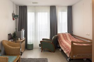 Eenpersoons slaapkamer met hoog/laag bed, grote ramen, tv meubel en 2 stoelen.