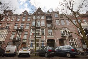 Een Amsterdams pand met vijf verdiepingen met daarvoor geparkeerde auto's.