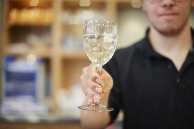 Een man met zwarte polo met in zijn hand een gevuld wijnglas.