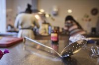 Schuimspaan op de voorgrond op aanrechtblad met op de achtergrond niet herkenbaar in beeld 2 dames