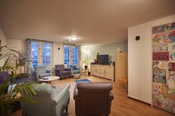 Gezamenlijke woonruimte met 5 sta op stoelen, een tv en een paar kasten.