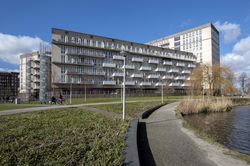 Breed gebouw aan het water met 6 verdiepingen en witte balkons