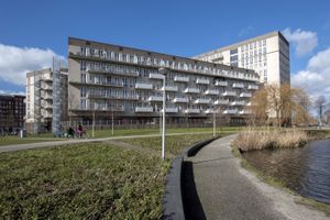 Breed gebouw aan het water met 6 verdiepingen en witte balkons