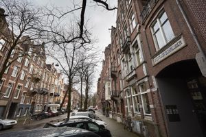 Een Amsterdams pand met vijf verdiepingen met daarvoor geparkeerde auto's.