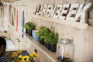 Een houten wand met planken en daarop potjes met verse kruiden en houten letters met de tekst Klarenbeek.