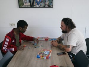 Twee mensen zitten tegenover elkaar aan tafel en maken een legpuzzel.