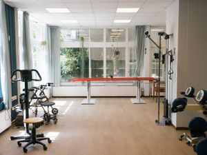 Een lichte sportruimte met daarin onder andere een loopbrug, een rollator en twee fietsmachines.