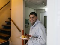 1 persoon staat glimlachend met zijn bord met eten voor de trap